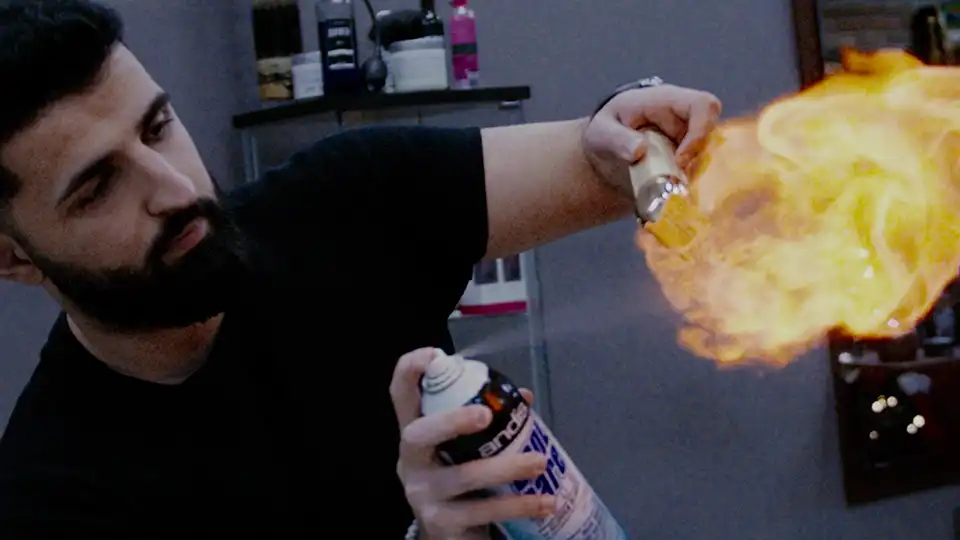 A barber spraying fire form a can